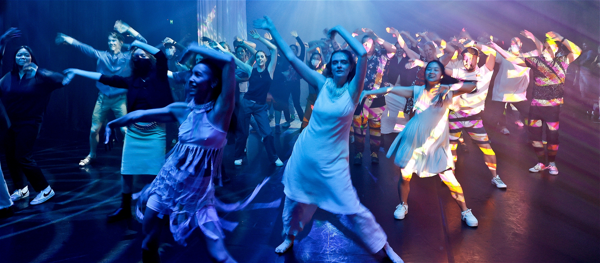 A multitude of dancers waving their arms in the air as they sway to the music
