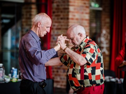 Two old men dancing; one seems to be teaching the other