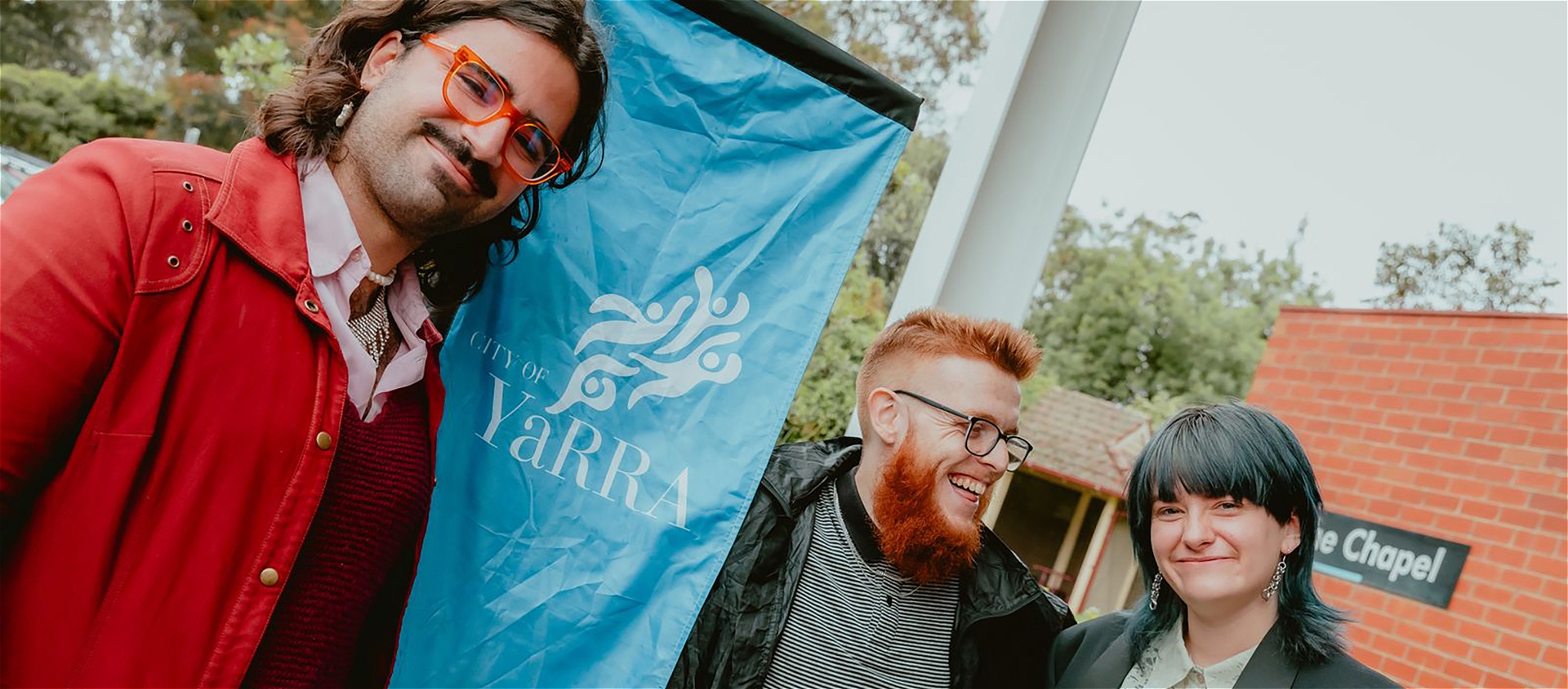 The people standing outside next to a City of Yarra Banner