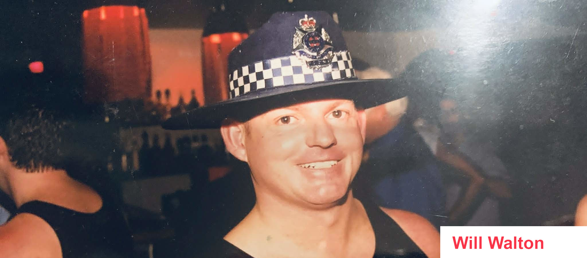 Will Walton cheekily wearing a singlet and the hat of a policeman