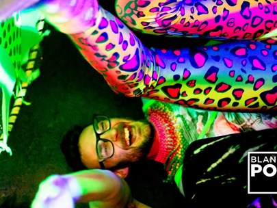 Man laying on his back laughing wearing and surrounded by bright vibrant UV colours