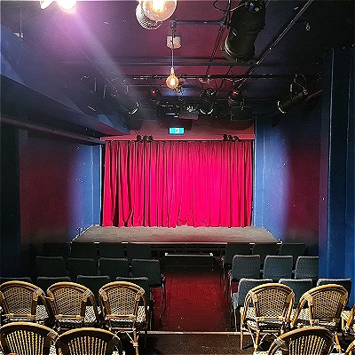 Stage with a red curtain behind it plus empty seats in the foreground