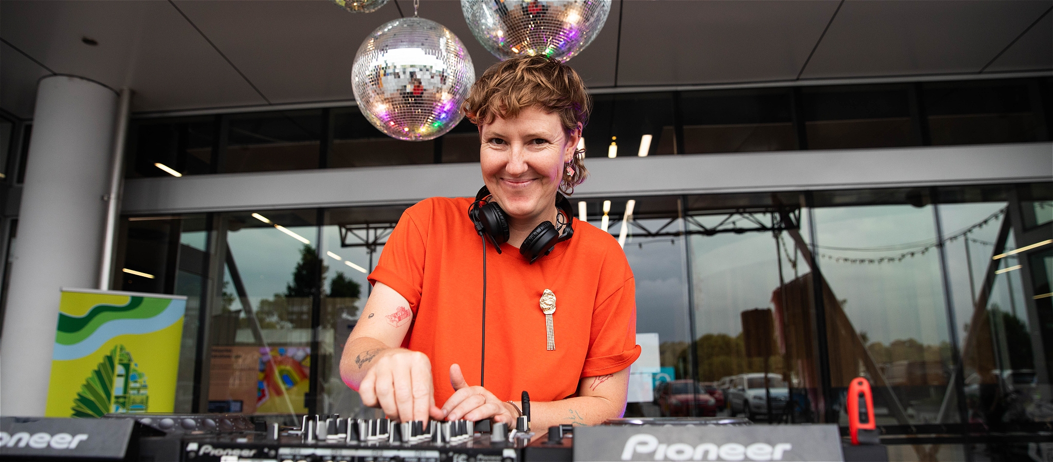 Smiling DJ twists knobs under mirror balls