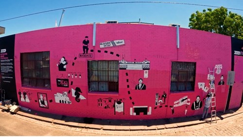 Corner building, painted pink with lots of graphic artwork on it