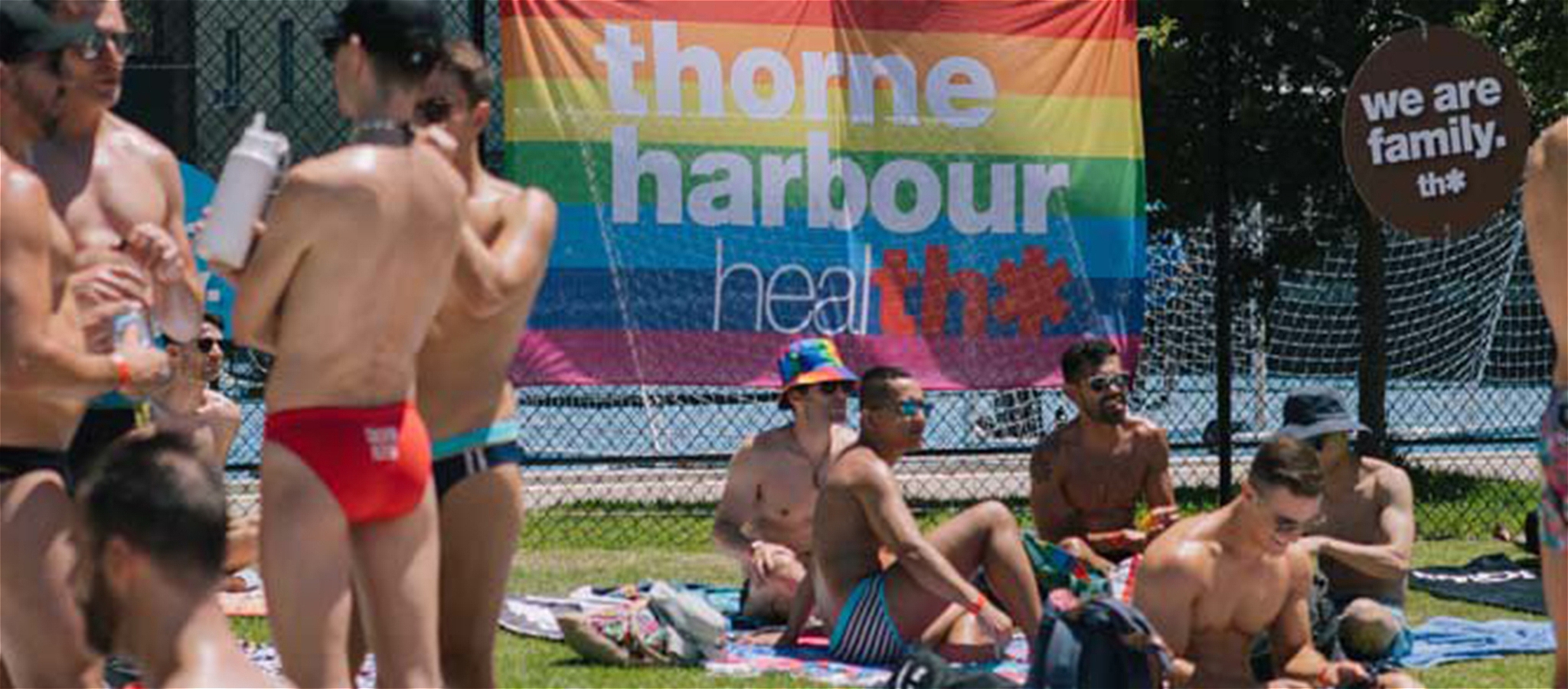 Groups of people siting and standing on the grass outside in the sun.