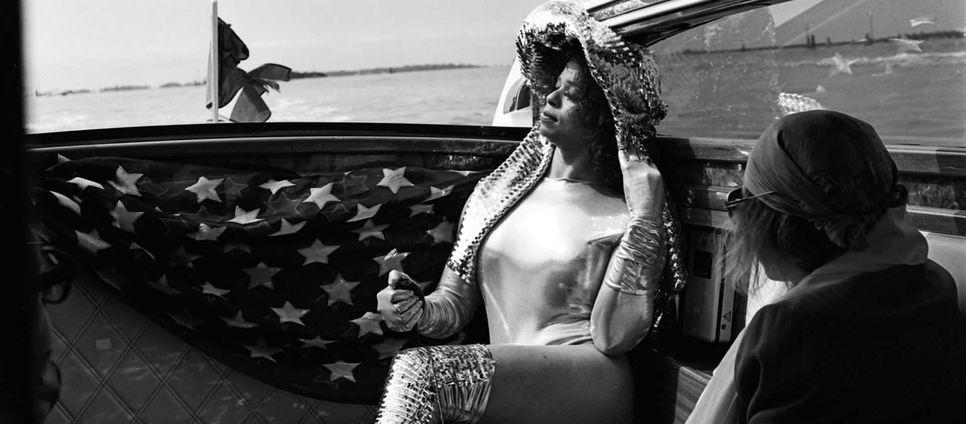 A woman wearing a hat, sitting on a boat looking out into the distance.