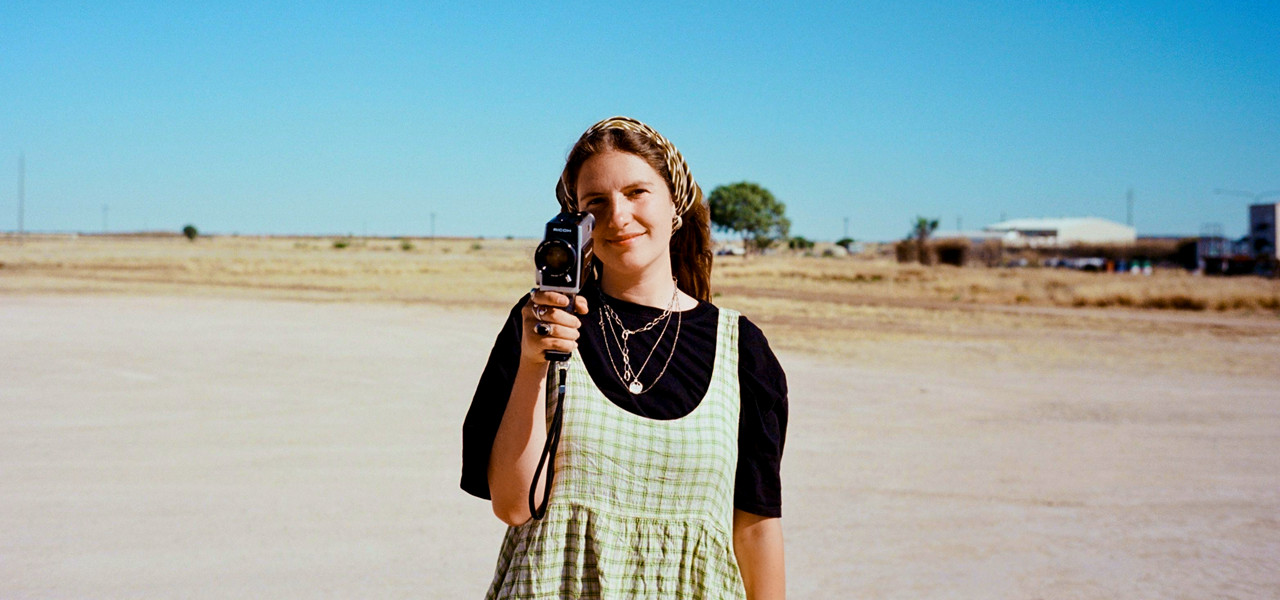 Emily in an Outback Australia setting pointing a video camera at the person taking this photo