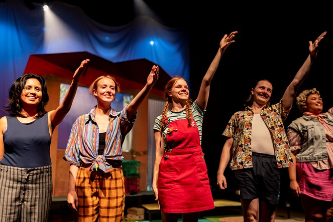 Five people on stage with arms outstretched in a welcoming gesture