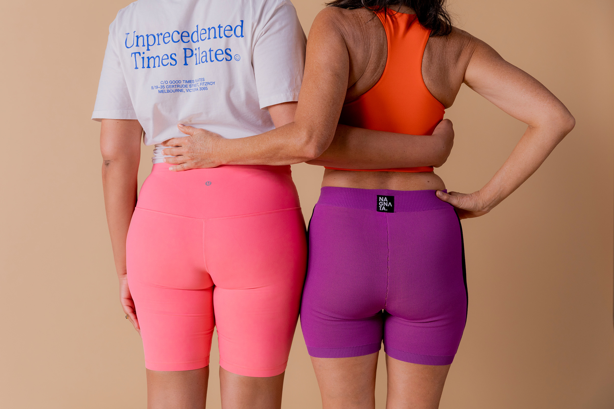 Two people facing away from the camera, arms wrapped around each other, wearing exercise gear