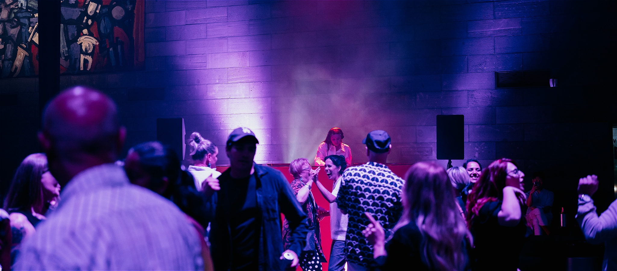 A crowd dancing in front of a DJ booth