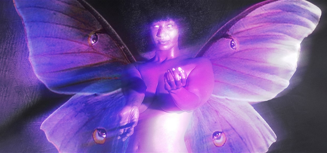 A naked purple skinned woman with white eyes and butterfly wings reaching out to the camera.
